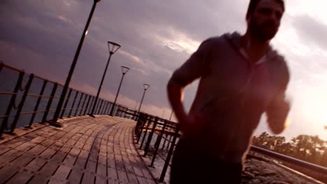 Young-fit-man-running-and-listening-to-music-at-sunset