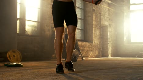 Hombre-ajuste-camisa-atlética-ejercicios-con-salto-/-saltar-cuerda-en-un-gimnasio-de-Hardcore-de-fábrica-abandonada.-Está-cubierta-en-el-sudor-de-su-intenso-entrenamiento.