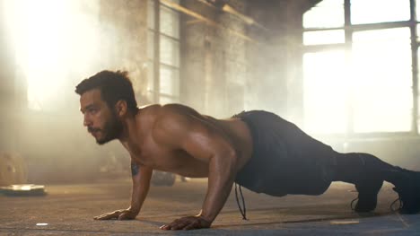 Muscular-Shirtless-Man-Covered-in-Sweat-Does-Push-ups-in-a-Deserted-Factory-Remodeled-into-Gym.-Part-of-His-Fitness-Workout/-High-Intensity-Interval-Training.