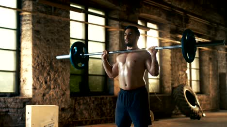 Strong-Athletic-Shirtless-Man-Lifts-Heavy-Barbell-as-a-Part-of--Fitness-Training-Routine.-Gym-is-in-Remodeled-Factory.