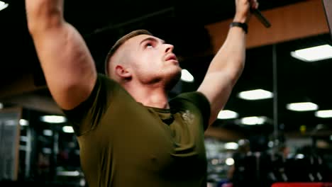 Young-handsome-blonde-man-iexercising-his-chest-muscles-and-training-his-shoulders-in-the-gym.-Shot-in-4k