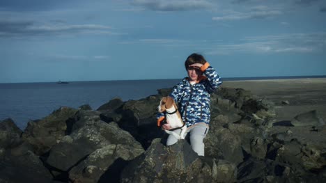 4K-im-freien-Meer-Kind-und-Hund-auf-Felsen-posieren
