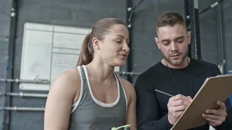Handsome-Coach-Instructing-Young-Woman-before-Workout