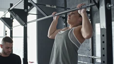 Strong-Woman-Doing-Chin-Up-Exercise-with-Coach
