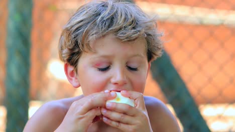Close-up-of-child-eating-healthy-fruit-outdoors-in-the-sunlight.-Young-boy-eating-oranges-outside-in-the-sunlight-in-4K
