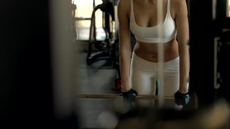 Sexy-woman-making-incline-with-barbell-and-looking-in-mirror-on-gym-club