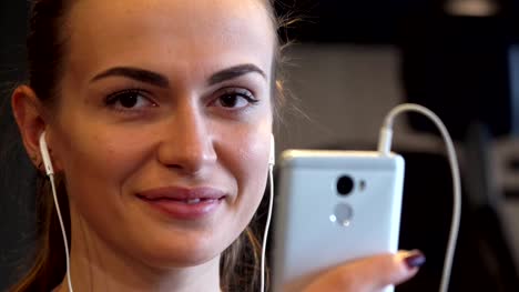 Close-up-of-a-smiling-girl-face-that-switches-something-in-the-phone