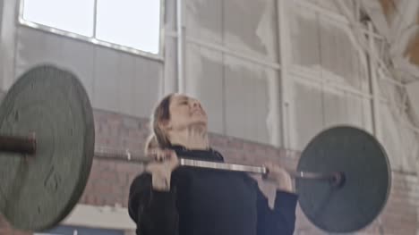 Gritty-Young-Woman-Raising-Barbell-Overhead