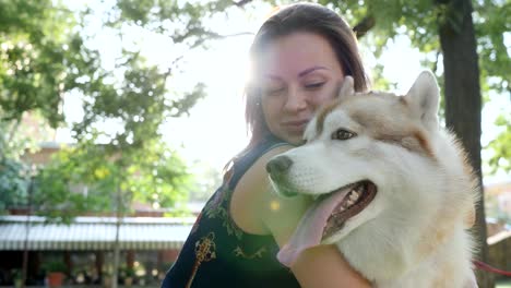 happy-girl-have-fun-and-hugging-husky-in-backlight-outdoors-close-up