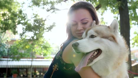 glückliches-Mädchen-viel-Spaß-und-umarmen-husky-bei-Gegenlicht-im-freien-close-up