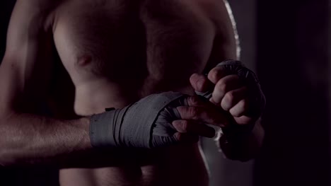 Male-boxer-wraps-his-hands-with-handwrap.-professional-boxer-wrapping-bandages-on-his-hand.-Fighter-wrapping-hands-with-boxing-wraps-in-the-gym