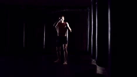 Kickboxer-shadow-boxing-as-exercise-for-the-fight.-Fighter-training-punching.-Boxing-in-the-darknes.-Young-boxer-training-in-the-gym