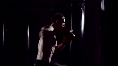 Boxer-punching-bag.-Slow-motion-sequence.-Strong-athlete-hits-a-punching-bag.-Kickboxing-men-training-punching-bag-in-fitness-studio.-Fighter-Training-Slow-Motion