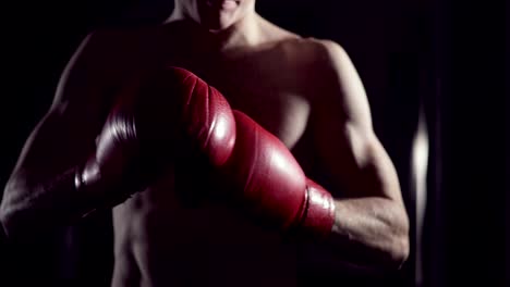 Boxer-puts-on-boxing-gloves.-Male-fighter-putting-his-gloves-on,-in-slow-motion.-Kickboxer-getting-ready-to-train-putting-on-gloves