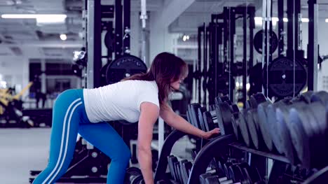 Mujer-fitness-ejercicios-en-los-músculos-de-la-espalda-con-mancuernas-en-el-gimnasio.-Deportista-haciendo-filas-One-Armed.-Hermosa-mujer,-levantamiento-de-pesas-en-el-Banco