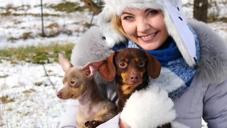 Mujer-jugando-con-sus-pequeños-perros-fuera-de-invierno