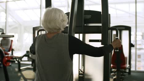Ältere-Frau-auf-Steigung-Brustpresse-im-Fitness-Studio