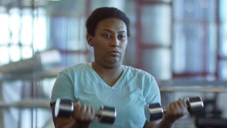 Woman-with-Dumbbells-Doing-Bicep-Curls-before-Mirror