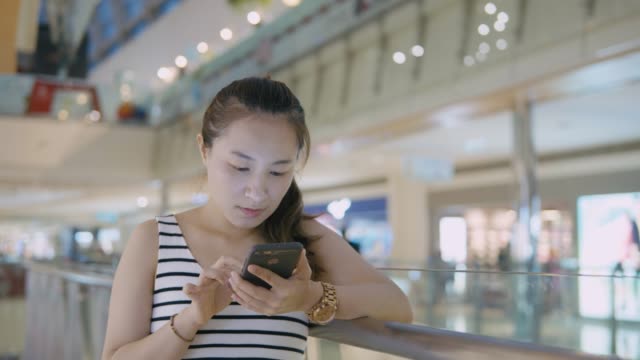 Woman-using-mobile-phone-in-the-mall