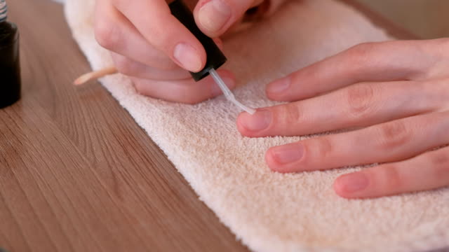 Woman-puts-a-base-coat-of-shellac-on-her-nails.-Close-up-hands.