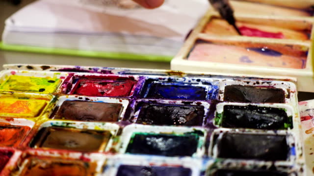 artist-blending-watercolors-on-a-palette-with-the-brush
