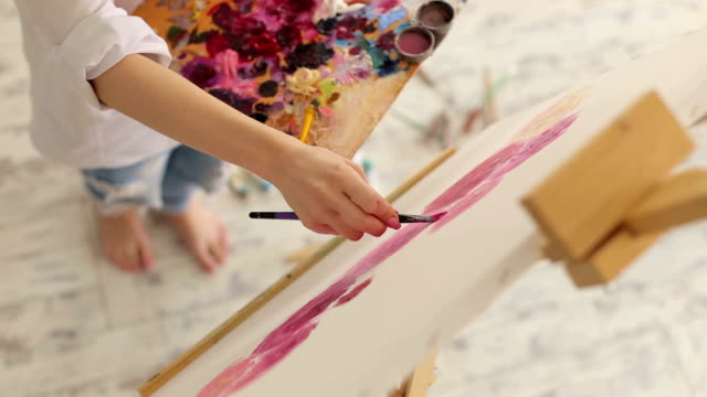 Frau-malt-Bild-auf-Leinwand-mit-Ölfarben-im-studio