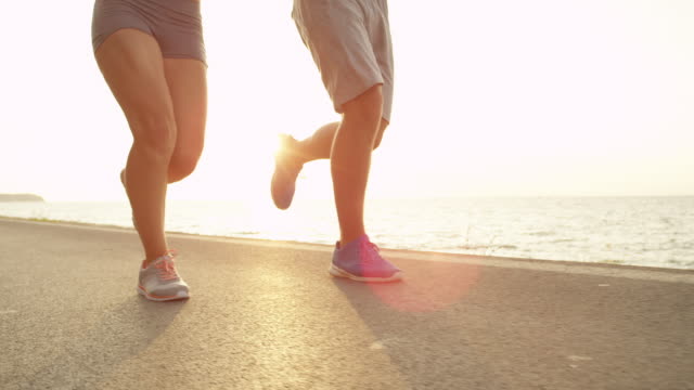 LOW-ANGLE:-Athletic-male-and-female-on-summer-vacation-running-along-the-coast.