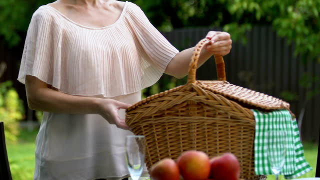 Pretty-lady-putting-picnic-basket-on-table,-man-hugging-her,-looking-at-camera