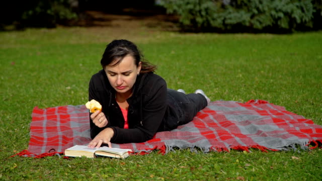 Mujer-leyendo-el-libro-y-comer-manzana