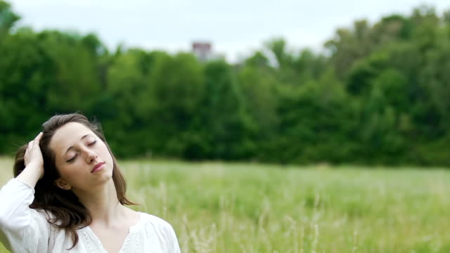 Deeply-relaxed-woman-in-green-field-touches-her-hair-with-eyes-closed-oneness