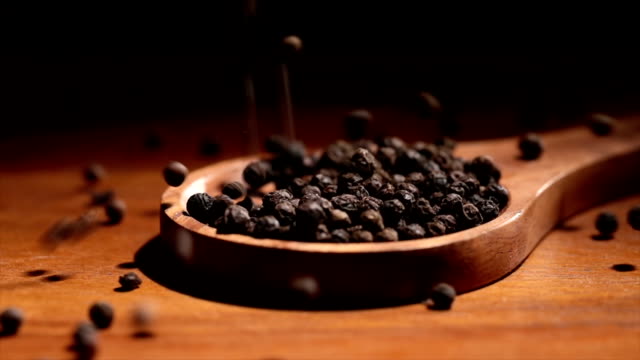 Black-Tellicherry-peppercorns-closeup-in-wooden-spoon-on-a-kitchen-table.