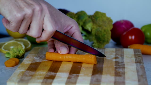 Man-is-cutting-vegetables-in-the-kitchen,-slicing-carrot