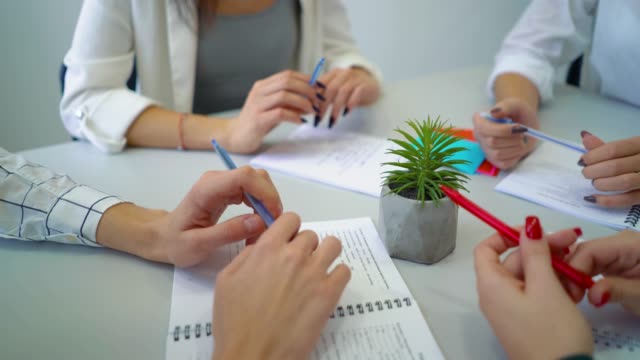 closeup-young-people-hands-with-pens-and-notebooks-on-table
