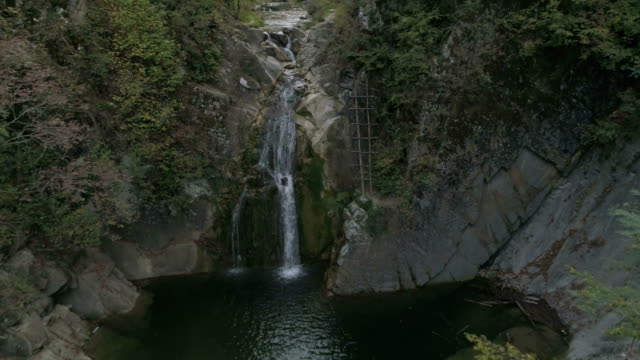 Luftaufnahmen:-ein-kleiner-Bach-fließt-in-einen-hohen-Wasserfall-mitten-im-Wald