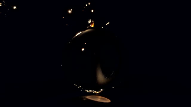 Brennende-Wunderkerze-hinter-eine-Glaskugel-auf-einem-schwarzen-Hintergrund.