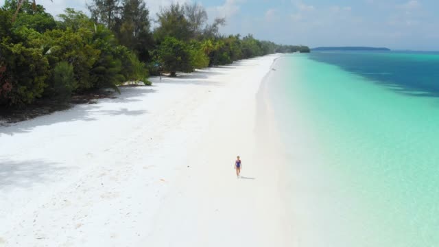 Aerial:-woman-walking-on-tropical-beach,-scenic-turquoise-water-and-white-sand,-Pasir-Panjang-Kei-Island,-Moluccas,-Indonesia,-paradise-travel-destination