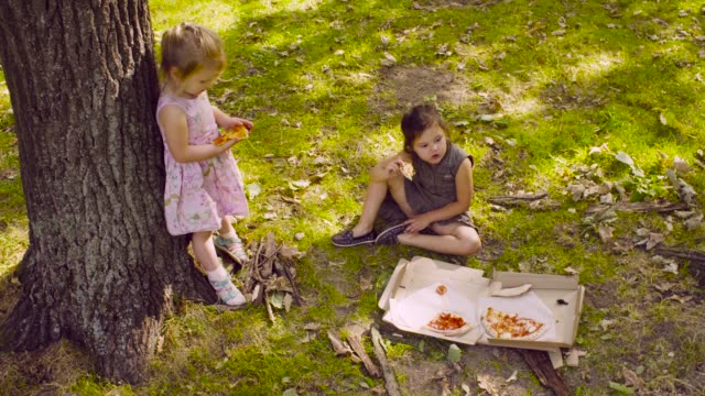 Zwei-Mädchen-im-Park-Pizza-essen.