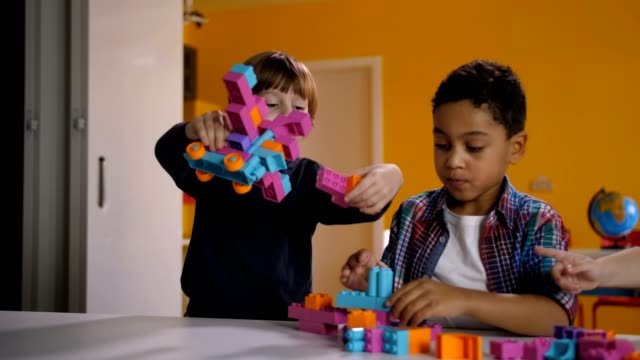 Two-diverse-kids-arguing-over-toy-in-kindergarten