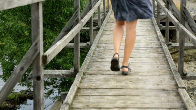 Woman-walking-along-old-wooden-bridge