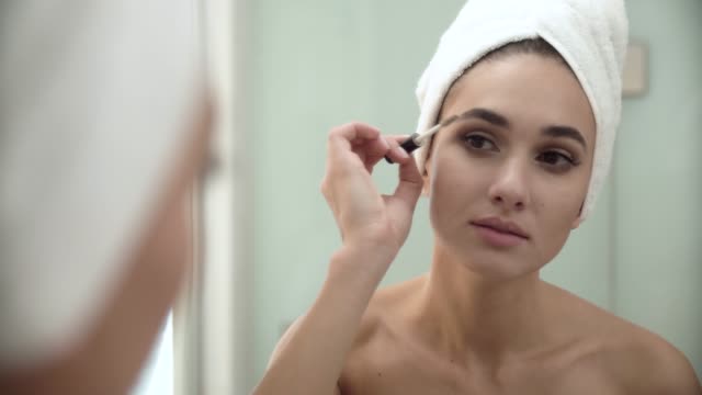 Schönheit-Make-up.-Frau-Bürsten-Augenbrauen-am-Badezimmerspiegel