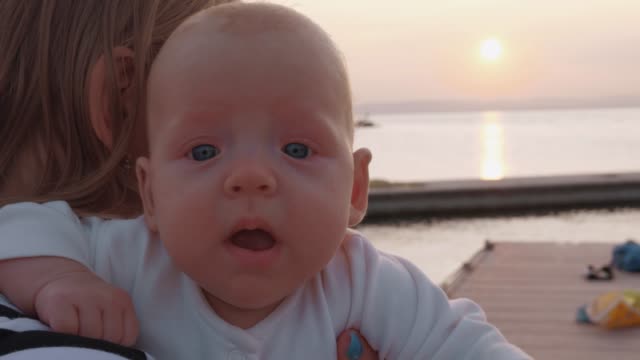 Baby-girl-in-mothers-hands-outdoor-at-sunset