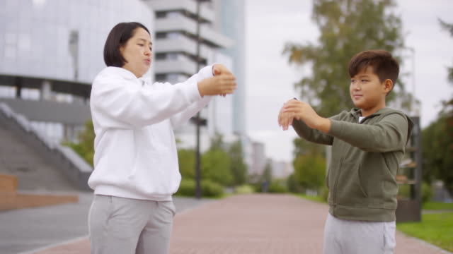 Asiatische-Frau-und-Junge-Stretching-Handgelenke-während-Outdoor-Training