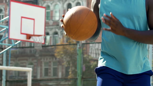 Starke-männliche-afroamerikanische-Kerl-spielt-Basketball-am-Sportplatz