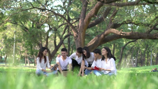 Six-students-meet-doing-homework-together.-People-meeting-team-in-the-park-outdoors.-Man-and-woman-using-laptop-computer.-Concept-of-education,-teamwork,-learning,-information,-knowledge-and-research.