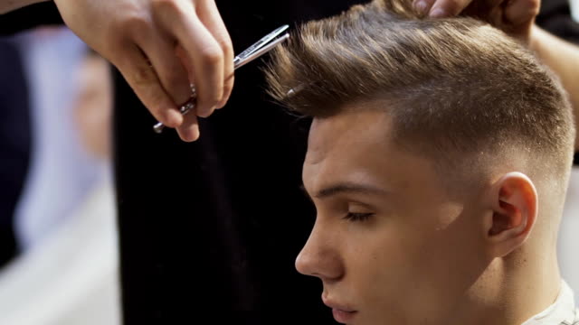 Friseur-schneidet-Haare-des-jungen-Mannes-mit-einer-Schere