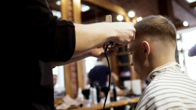 Friseur-schneidet-Haare-mit-elektrischen-Rasierapparat-für-junge-Kunden