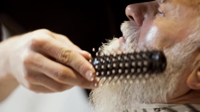 Barber-dries-and-combs-beard-of-mature-man