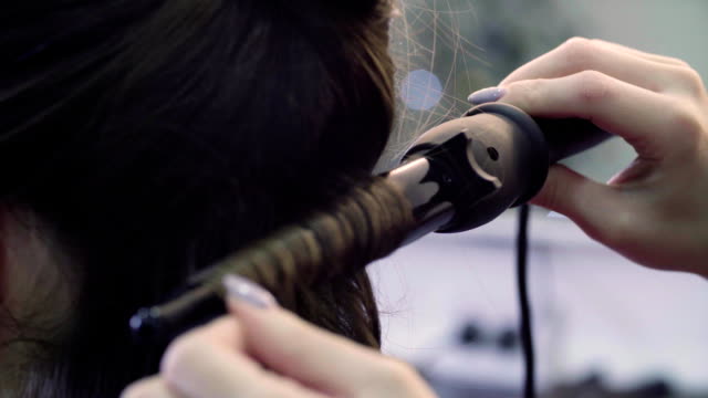 Hands-of-stylist-curling-hair-with-curling-tongs