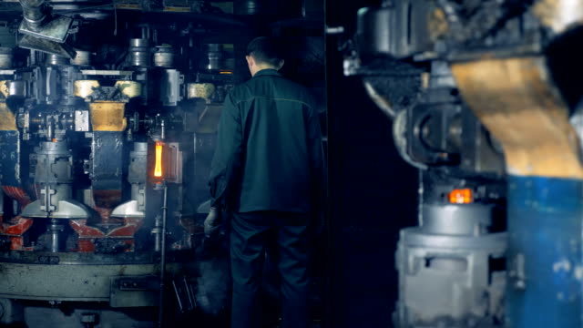 A-worker-watches-how-special-machine-melts-out-bottles-at-a-plant.-4K.