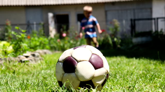 Kleiner-Junge-spielt-mit-Fußball-auf-dem-Rasen---Stock-video